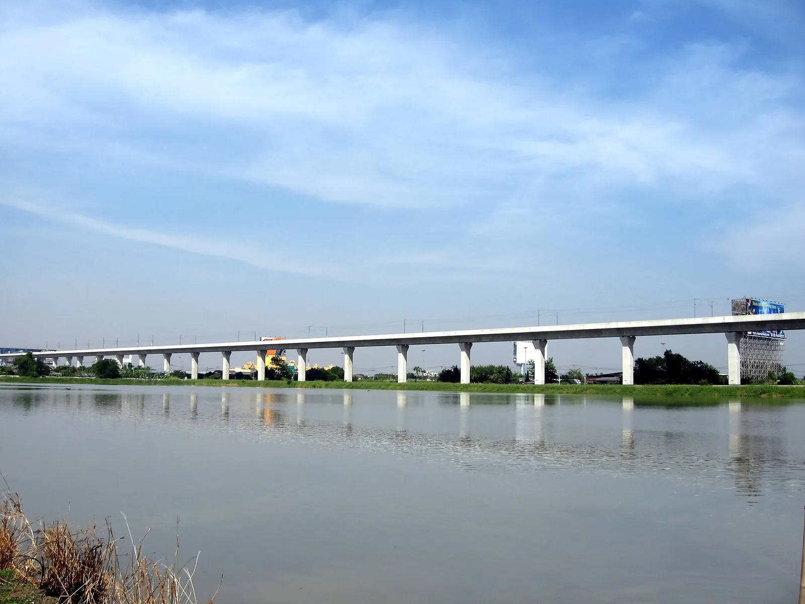 The elevated Airport Rail Link viaduct running towards Bangkok under blue skies