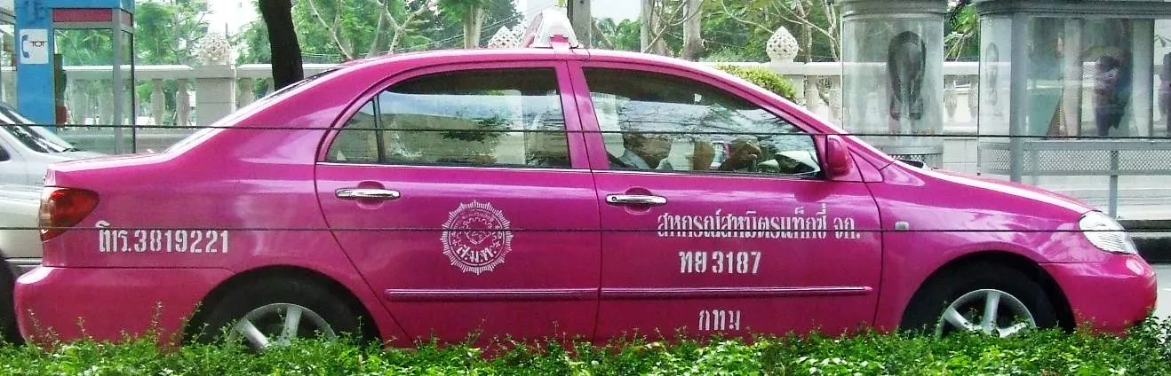 A bright pink metered taxi on a street in Bangkok, Thailand