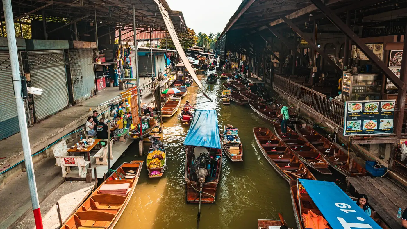 A wooden walkway and stalls beside a canal at a floating market in Thailand