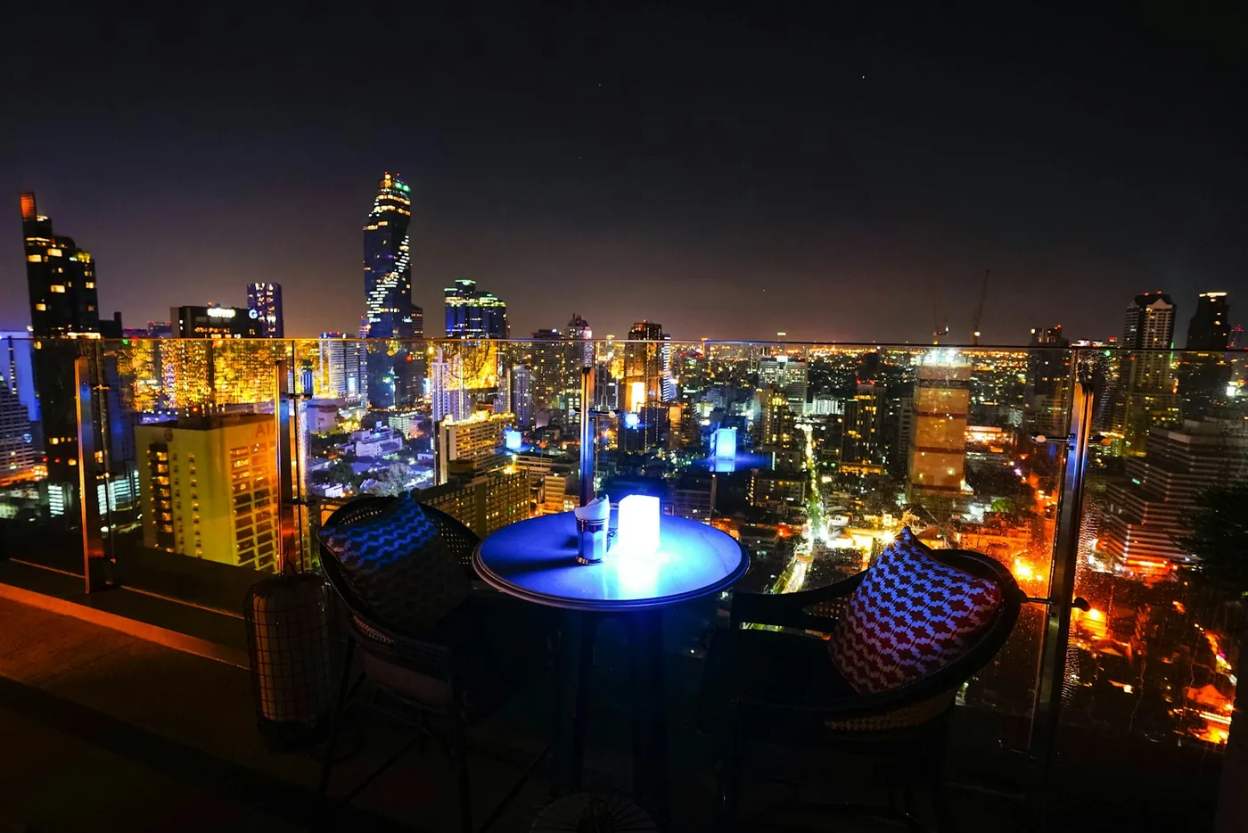 The Bangkok skyline lit up at night seen from a rooftop bar in Thailand