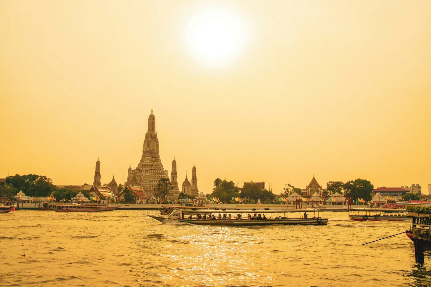 A ferry on the Chao Phraya river with temples on the bank in Bangkok, Thailand