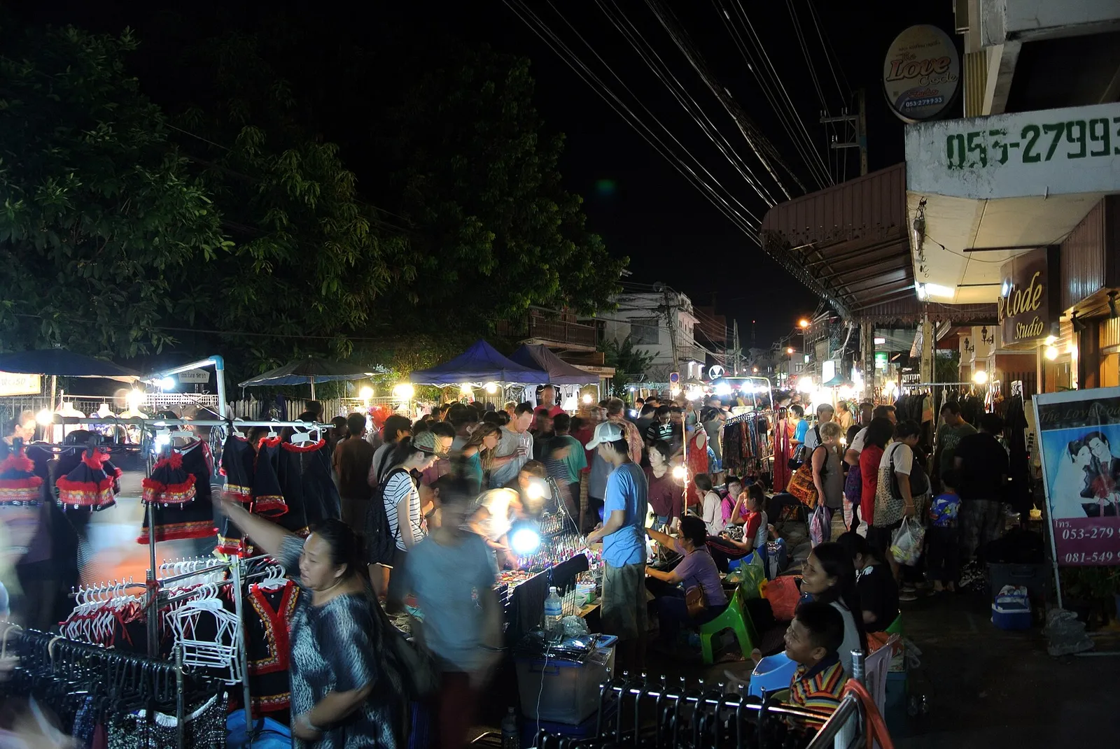 Craft and food stalls glowing under lights at a busy night market in Chiang Mai, Thailand