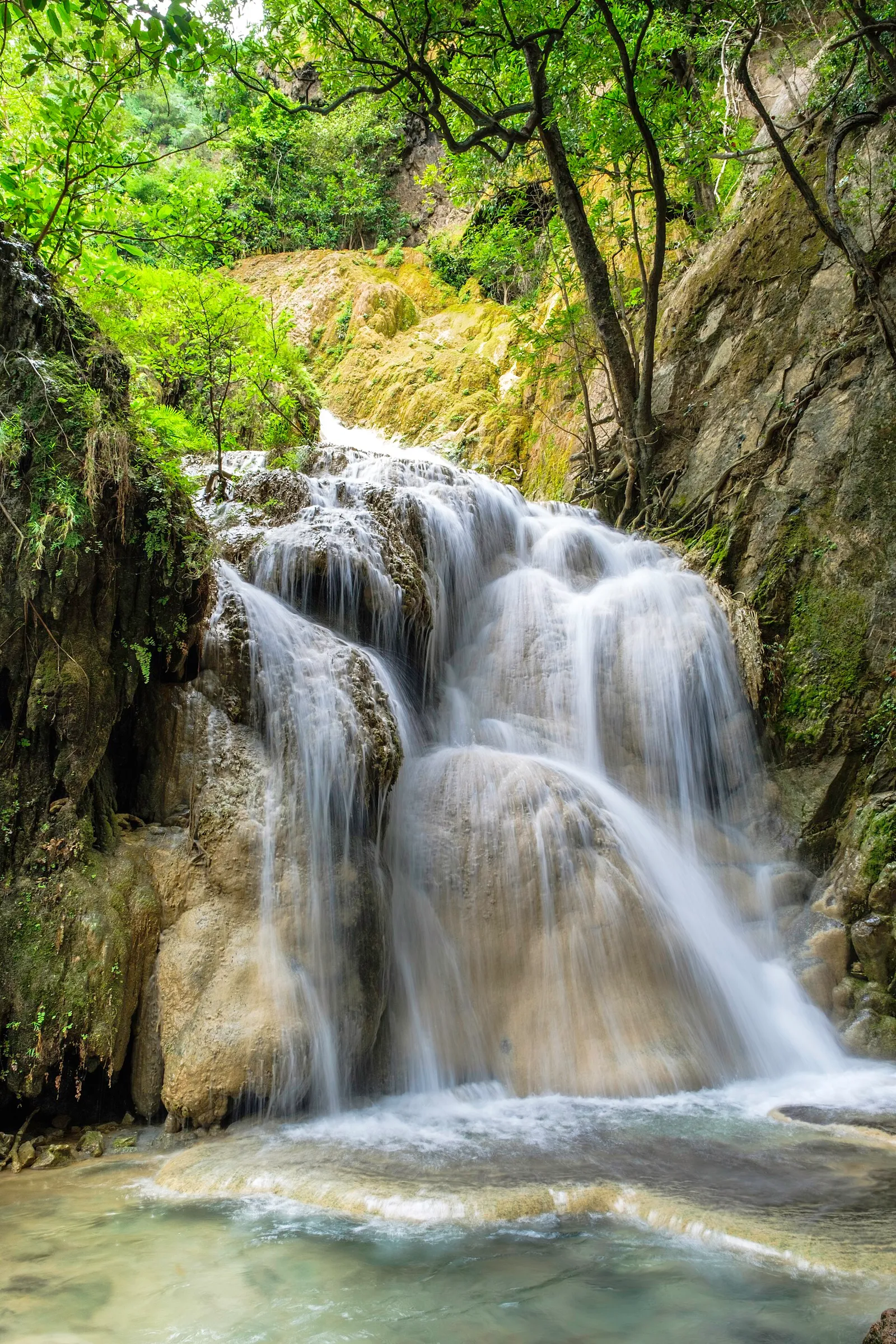 A wide waterfall tier surrounded by rainforest in a Thai national park