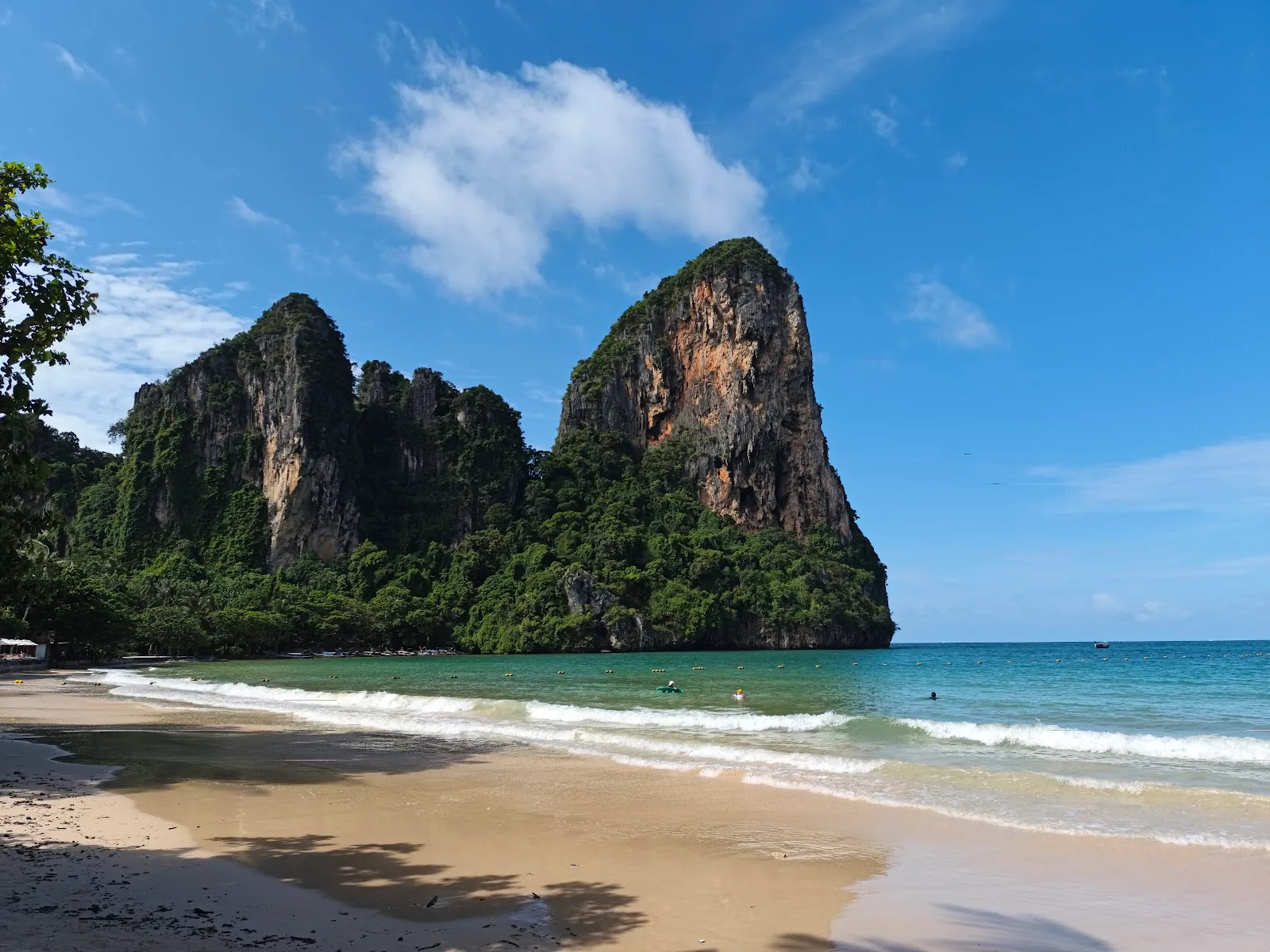 Railay beach in Krabi, Thailand, with limestone cliffs and a longtail boat on turquoise water