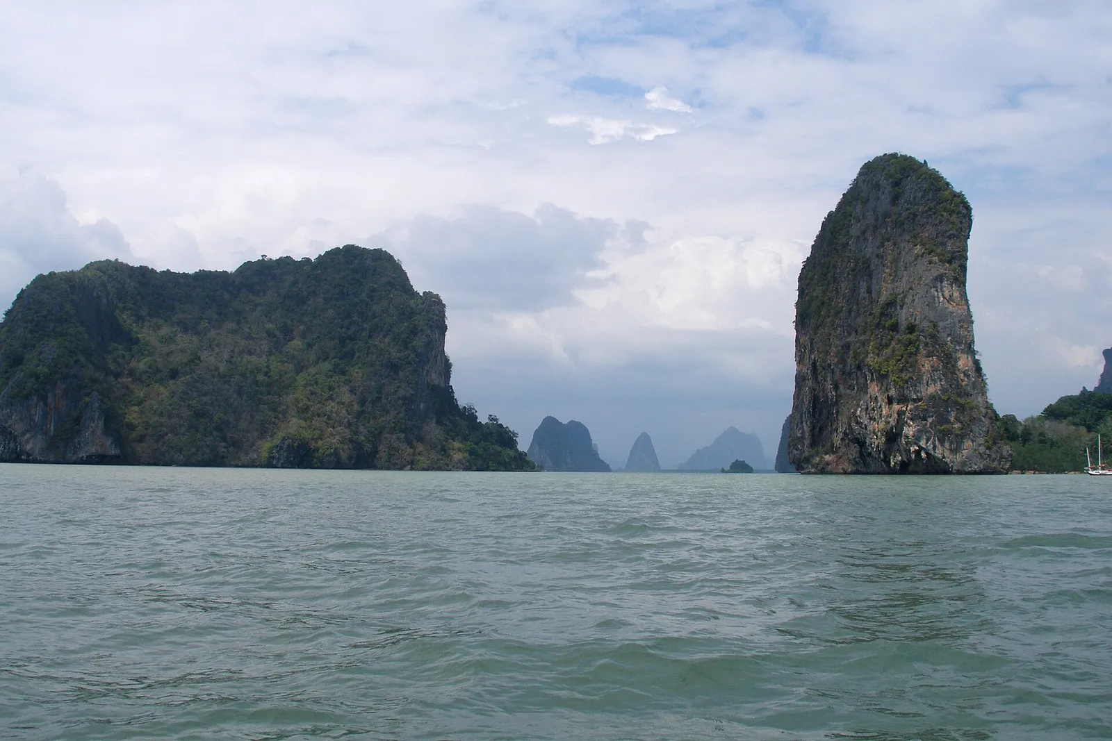 A longtail boat moored on a white sand beach beneath limestone cliffs at Phi Phi, Thailand