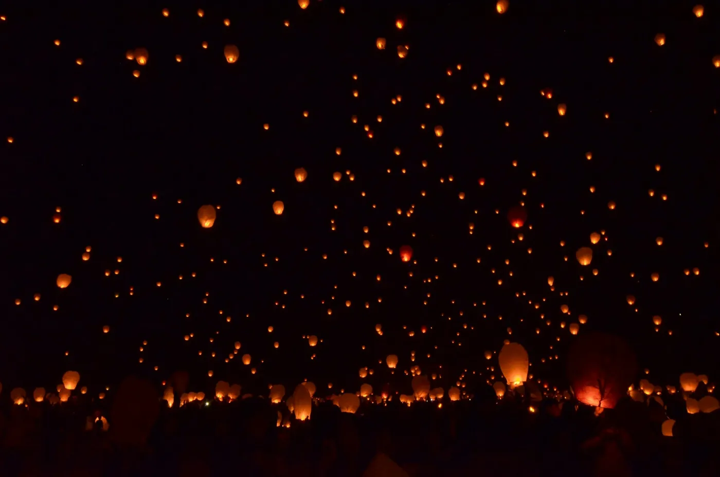 Paper sky lanterns rising together against a dark night sky