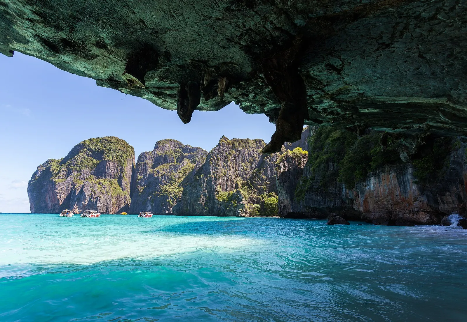 Maya Bay at Koh Phi Phi, Thailand, a cove ringed by vertical limestone cliffs with turquoise water and small tour boats
