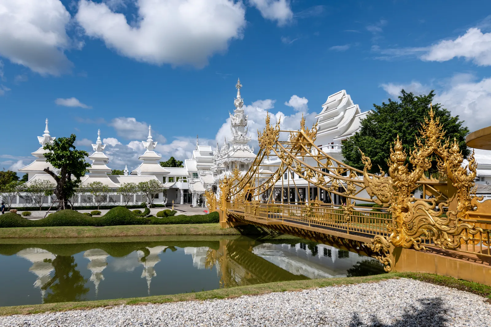 The intricate white carved facade and bridge of Wat Rong Khun, the White Temple, in Chiang Rai, Thailand