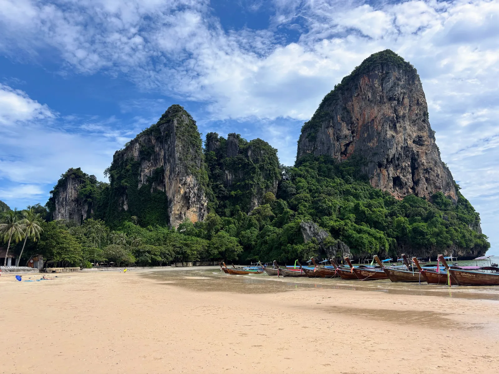 A longtail boat pulled up on the beach at Railay, backed by limestone cliffs