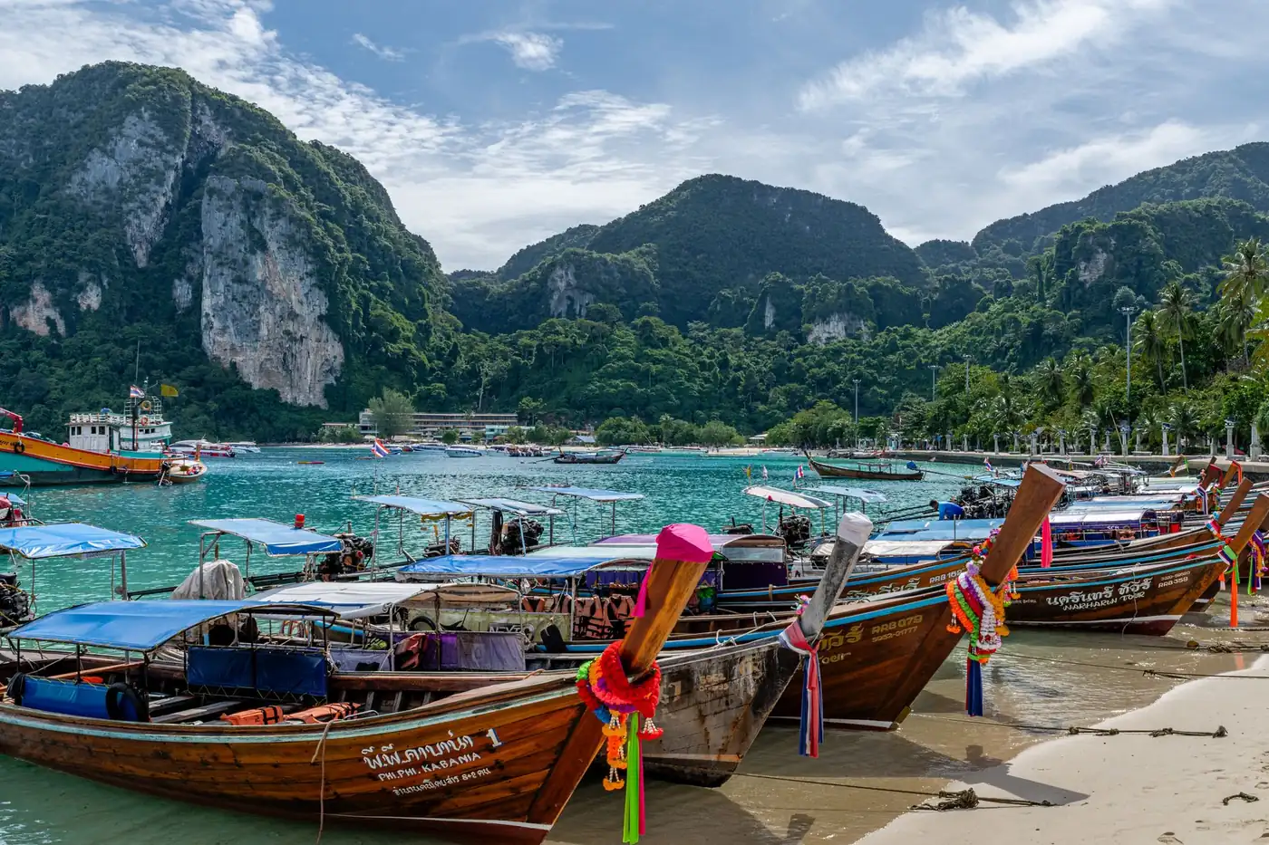 The long busy main beach with swimmers and longtail boats in Phuket, Thailand