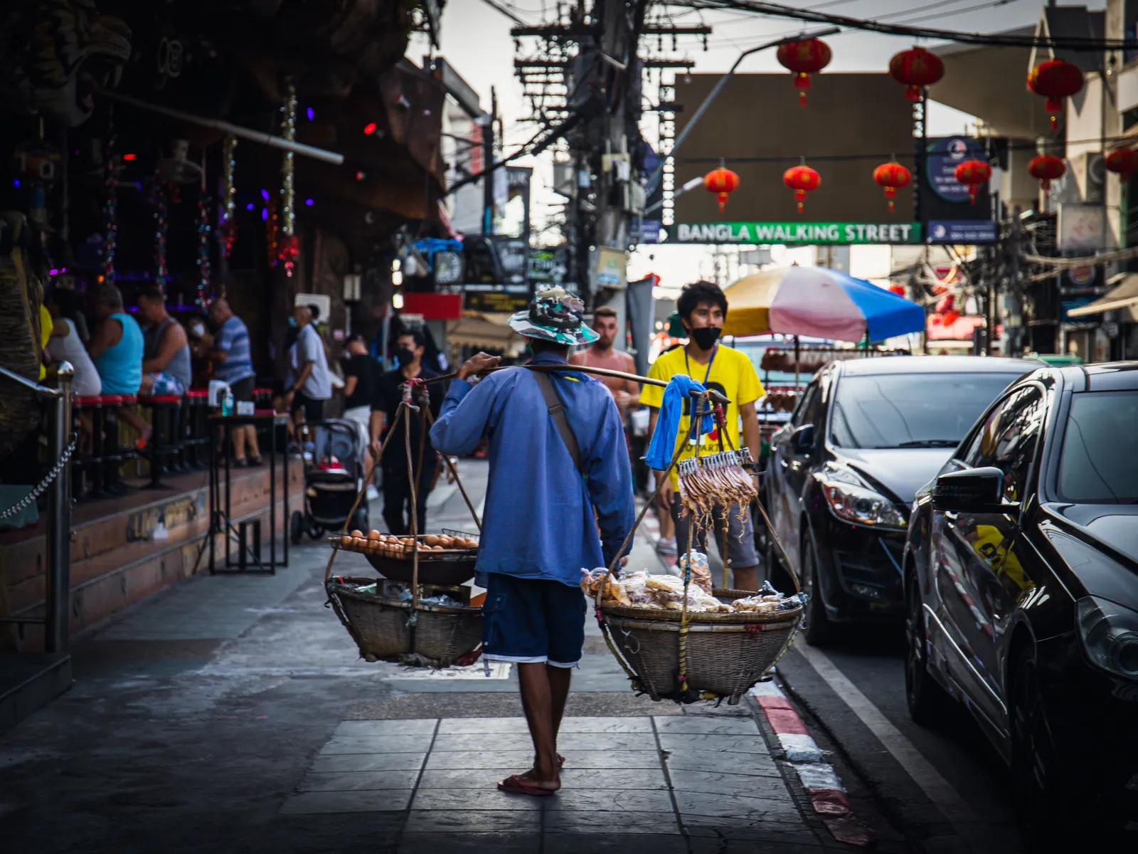 The entrance to Bangla Walking Street in Patong, Phuket, with a street vendor passing in daylight