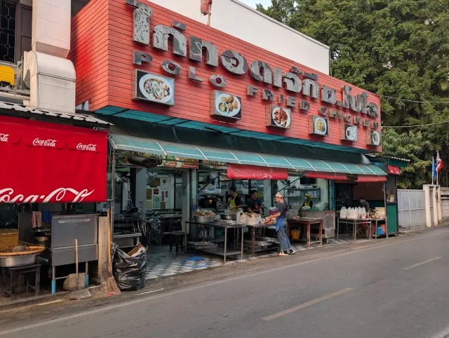 A red street restaurant front with green awnings and cooking stalls beside the road