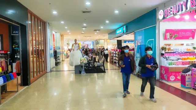 An indoor mall corridor with shops on both sides and visitors walking past