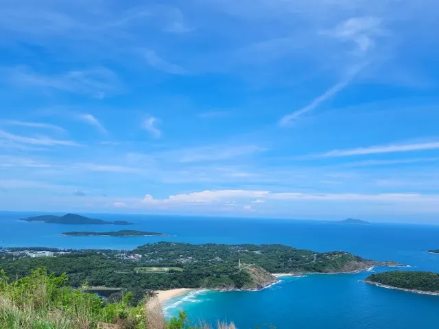 A high view over a green headland, blue bays and islands on the horizon