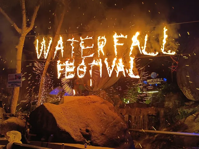 Letters burning with fire above a large boulder at night, with sparks in the air