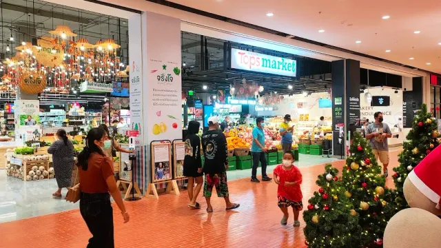 A supermarket entrance inside a mall, a decorated fir tree and shoppers in the open concourse