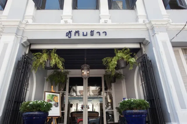A white Sino Portuguese style entrance with hanging ferns and blue planters