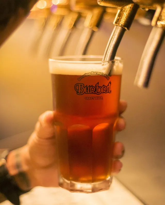 A glass of amber beer poured from a bar tap in warm light