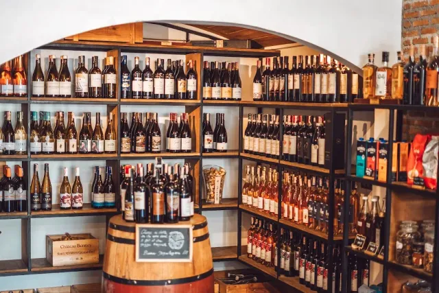 Wooden shelves loaded with wine bottles and a wooden barrel with a small chalkboard