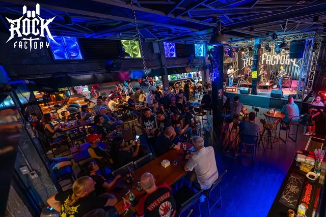 A live music hall seen from above, a band on a blue-lit stage and a crowd at tables