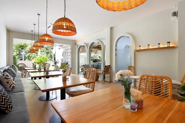 Orange rattan lamps above wooden tables, a bench with cushions and white arches