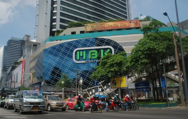 A large shopping centre building with oversized signage and traffic on the street in front