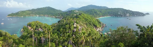 A high view over two twin bays with a narrow sand spit between green hills