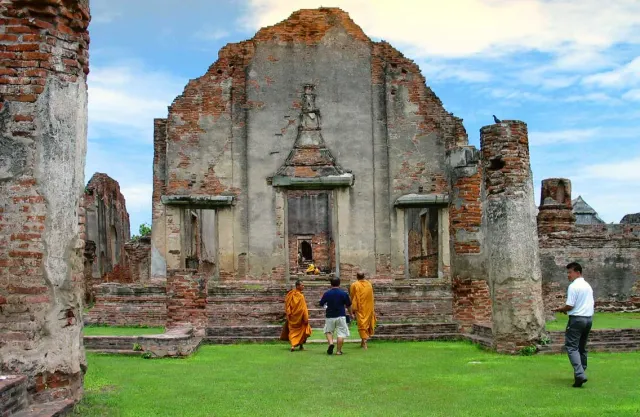 Red brick ruins of a prang and temple halls standing on a green lawn