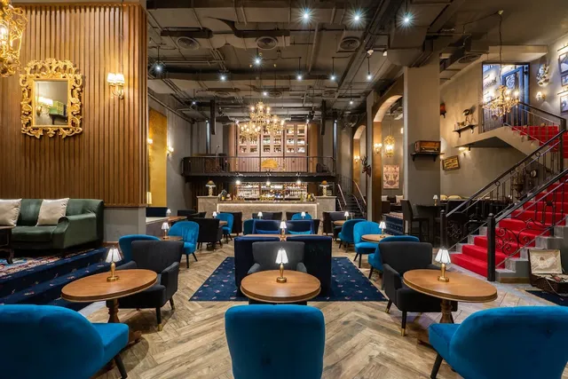 A hall with blue velvet armchairs, chandeliers and stairs with a red carpet