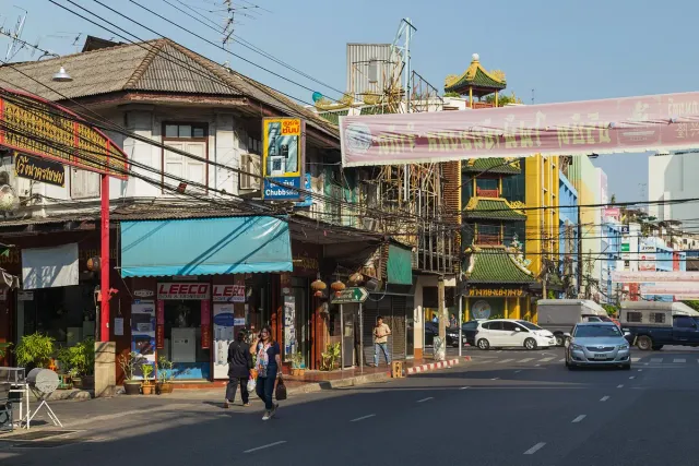 A city street lined with shophouses, colourful Chinese signage and light traffic