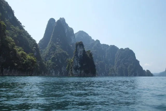 Green limestone cliffs rising from still water across a wide lake valley