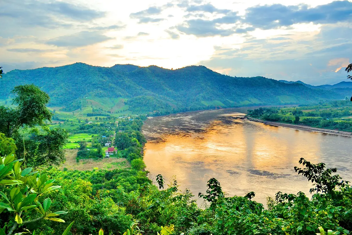 Hilltop view over a wide glowing river bend between green hills and mountains
