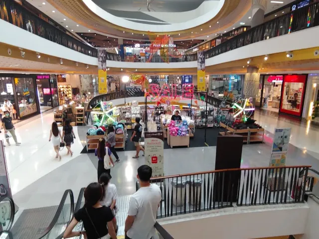 A view from an escalator onto a mall concourse with shops and sales stands