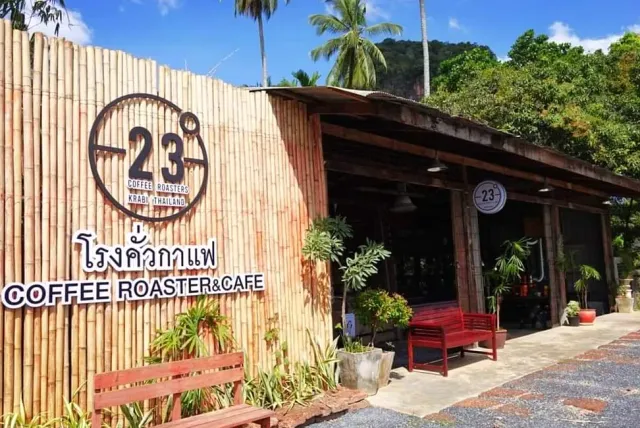 A bamboo fence with a round sign, an open wooden building and a red bench outside