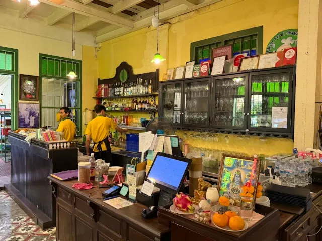 A hall with yellow walls, a dark wooden counter with bottle shelves and waiters in yellow shirts
