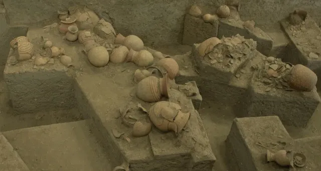 An excavation pit with ancient clay pots and pottery fragments exposed in the earth layers