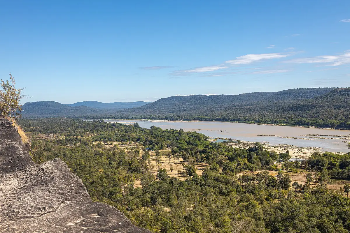 Clifftop view over forest, a wide river and blue hills on the horizon