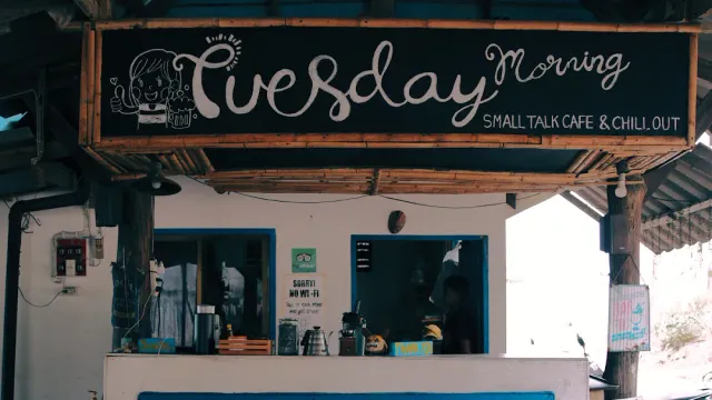 A black wooden hand painted sign above the open counter of a cafe