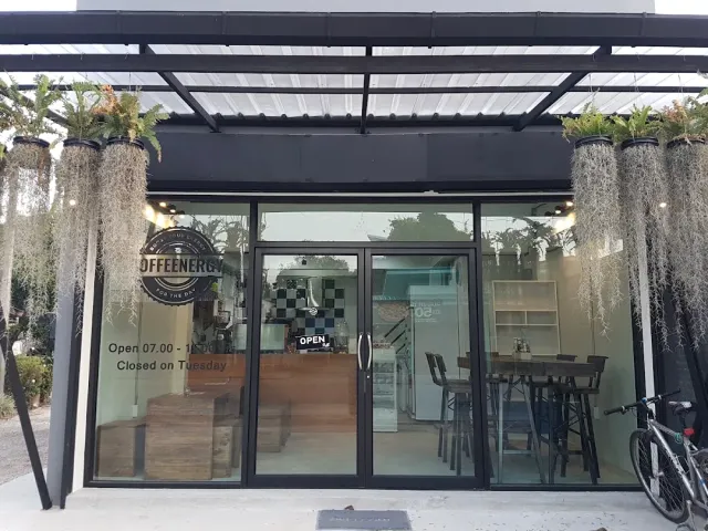 A glass storefront with a round sign, plants hanging from the canopy and a bicycle to the side