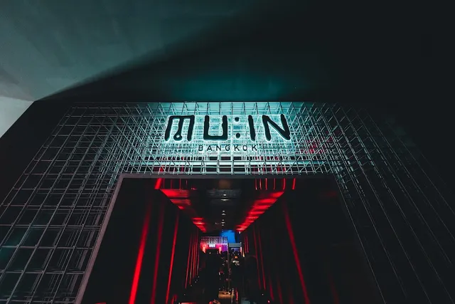 An entrance lit by a sign on a metal grid, with a red passage leading into the club