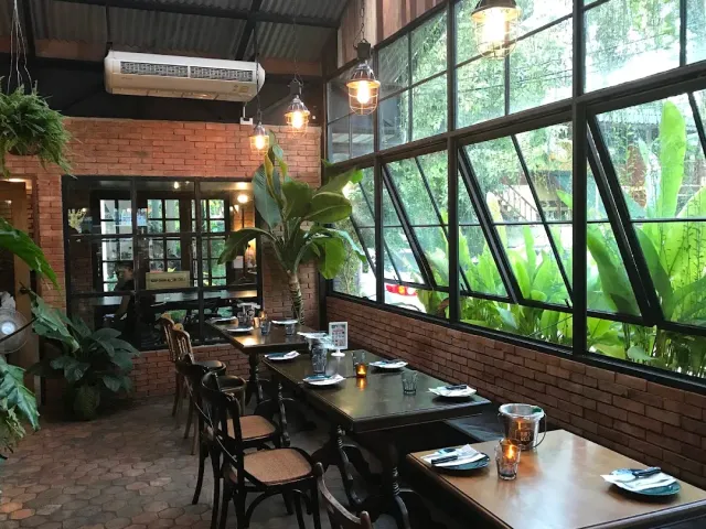 A dining room with red brick walls, slanted windows and set tables