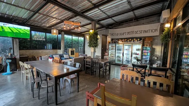 A space with a tin ceiling, long tables and lit drink fridges on the back wall