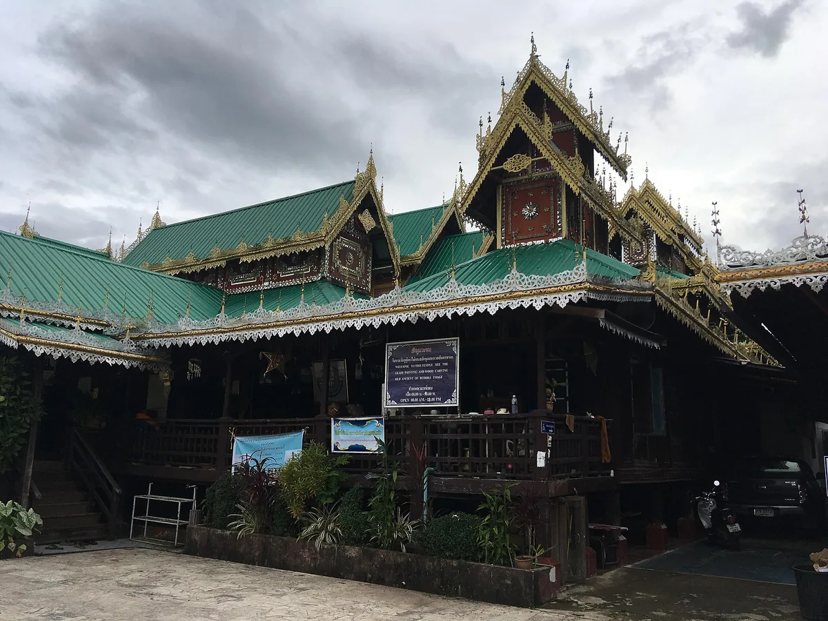 A wooden temple hall with a tiered green tile roof and gilded gable ornaments