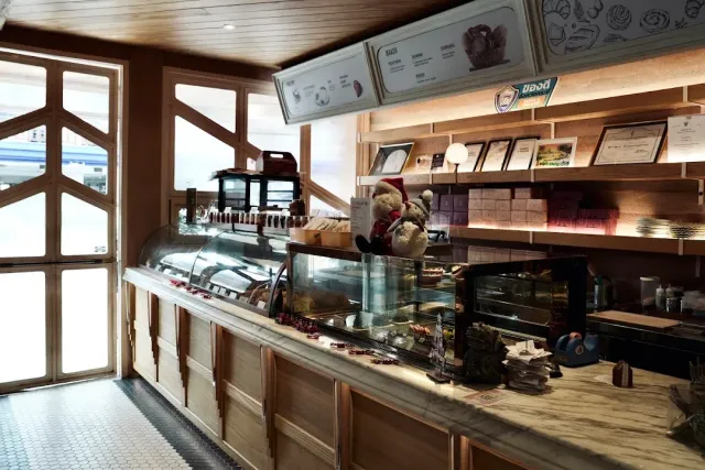 A long marble counter with pastry display cases, shelves of certificates and a stuffed teddy bear