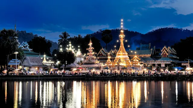 Gilded temples lit at dusk and mirrored in the lake water in front of them