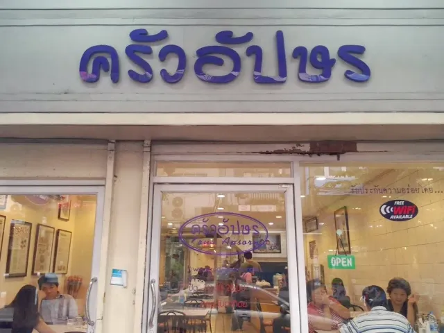 A white shopfront with a Thai script sign and diners visible through the window