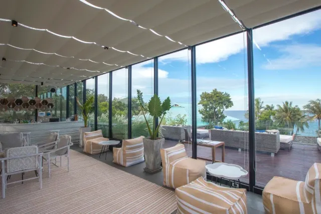 A covered terrace with striped armchairs, glass walls and an open sea view