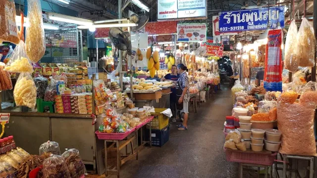A covered aisle with dry food stalls hanging in bags and colorful signs above