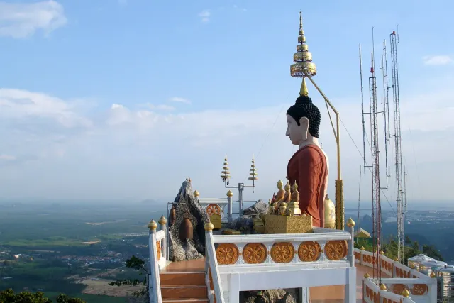 A gilded Buddha figure on a hilltop with an open view over the plain below