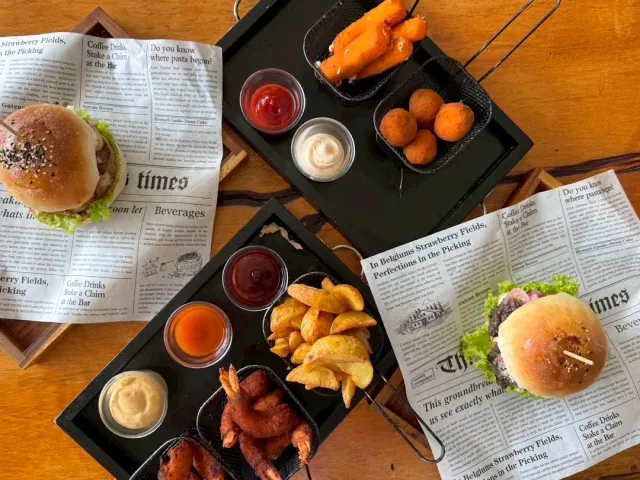 An overhead view of two burger trays with fries, fried balls and sauces